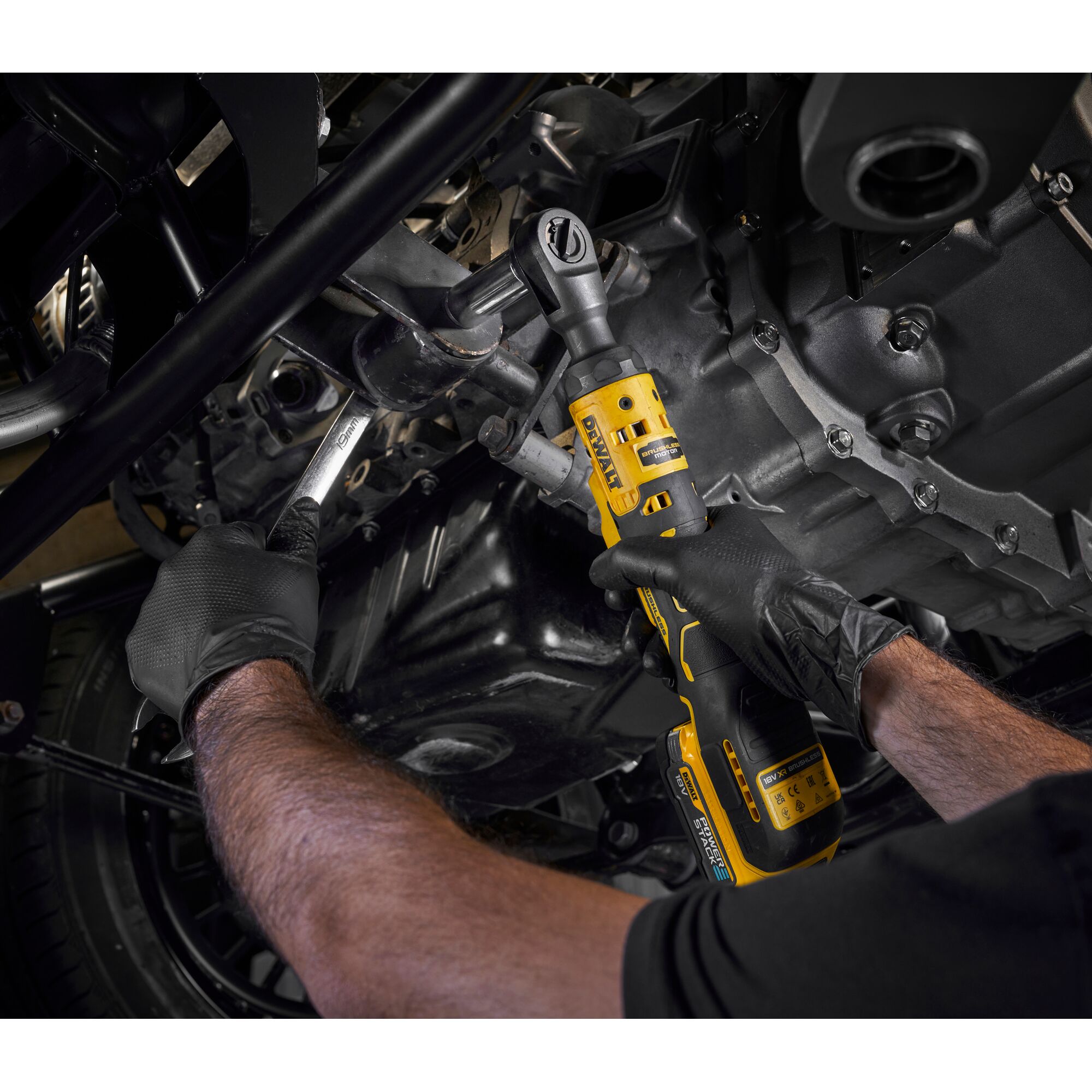 Person uses a DEWALT cordless ratchet tool DCF512N on an engine while wearing gloves.