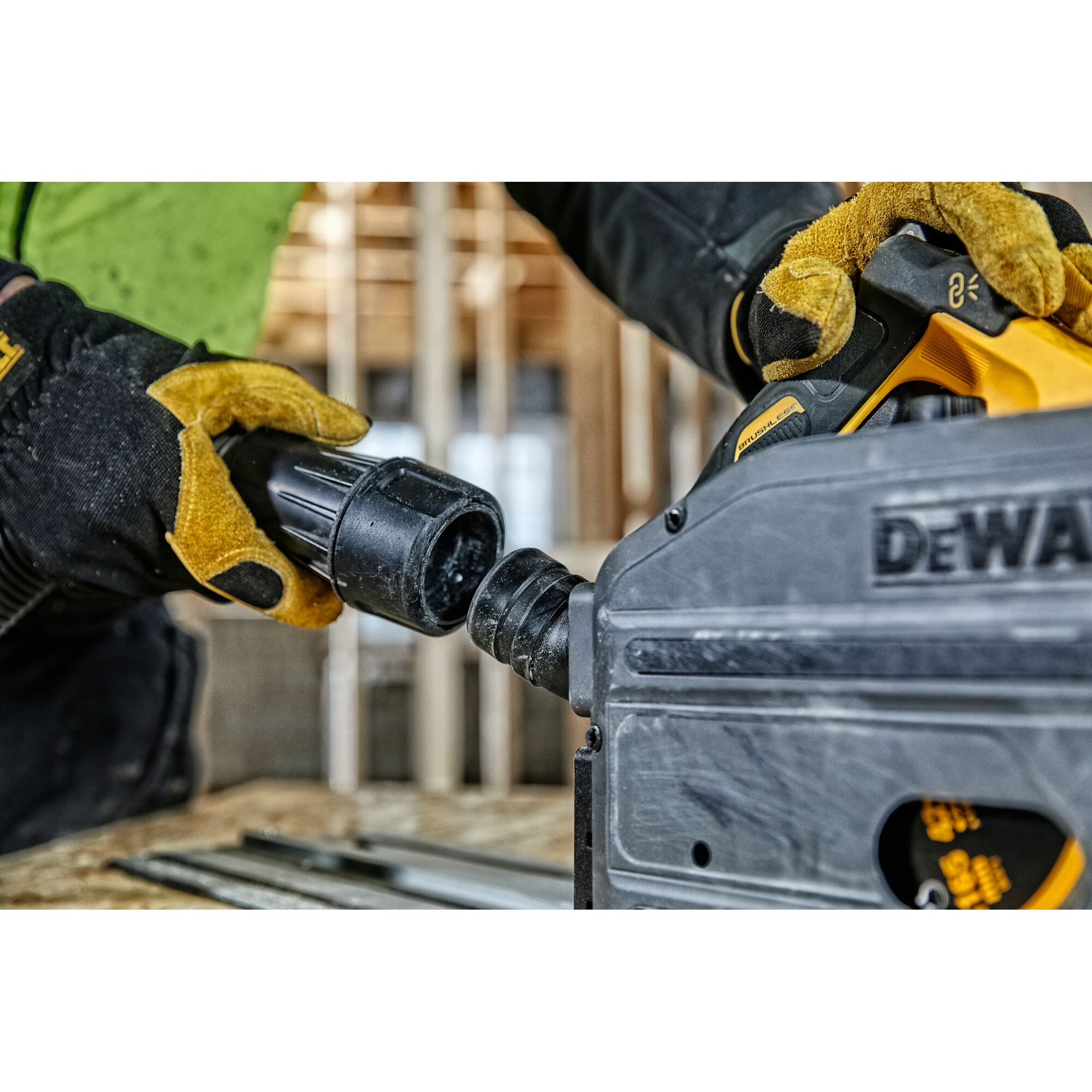 Gloved hands connecting a hose to a DEWALT power tool in a construction setting.