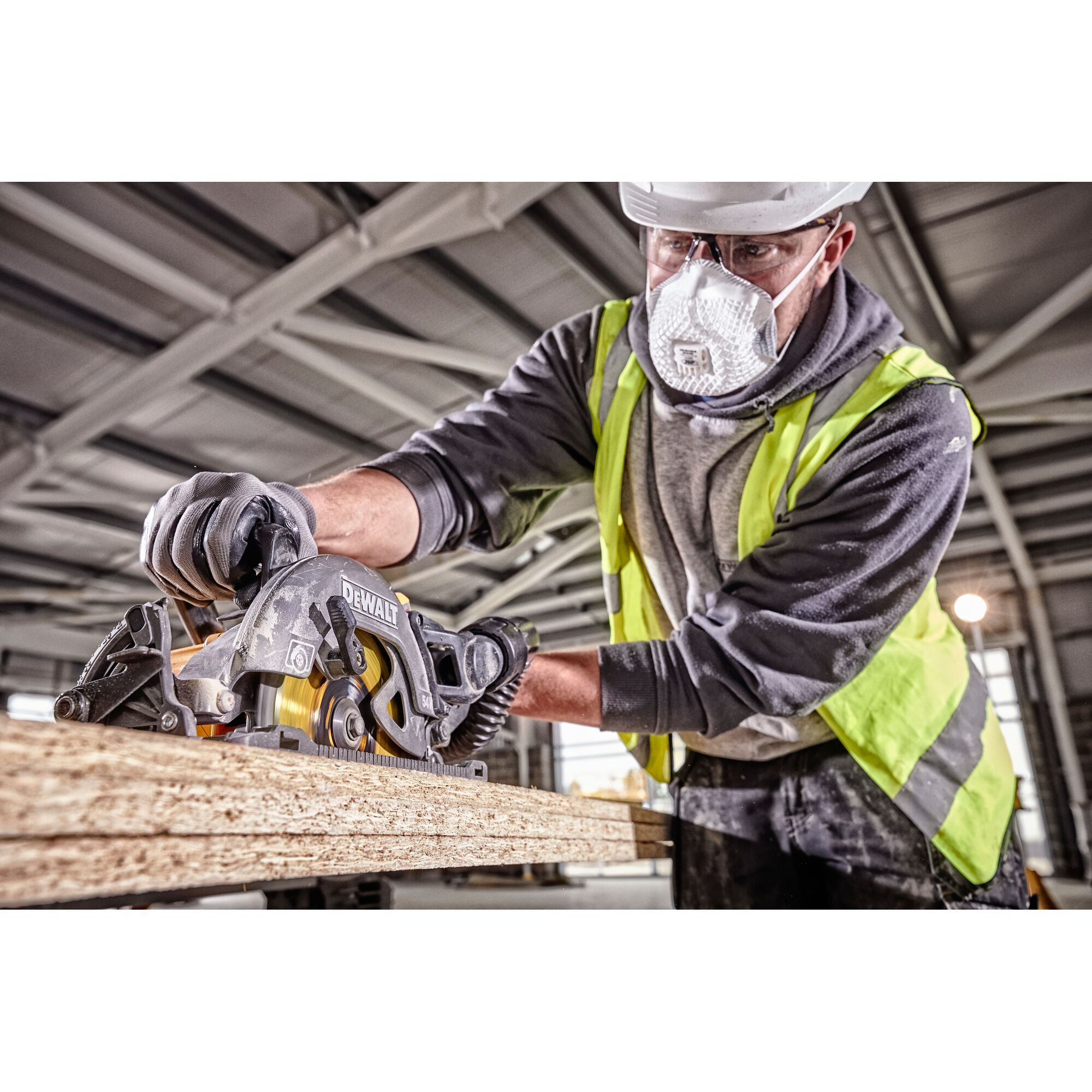 Worker using a DEWALT circular saw to cut wood on a construction site. Face is blurred for privacy.