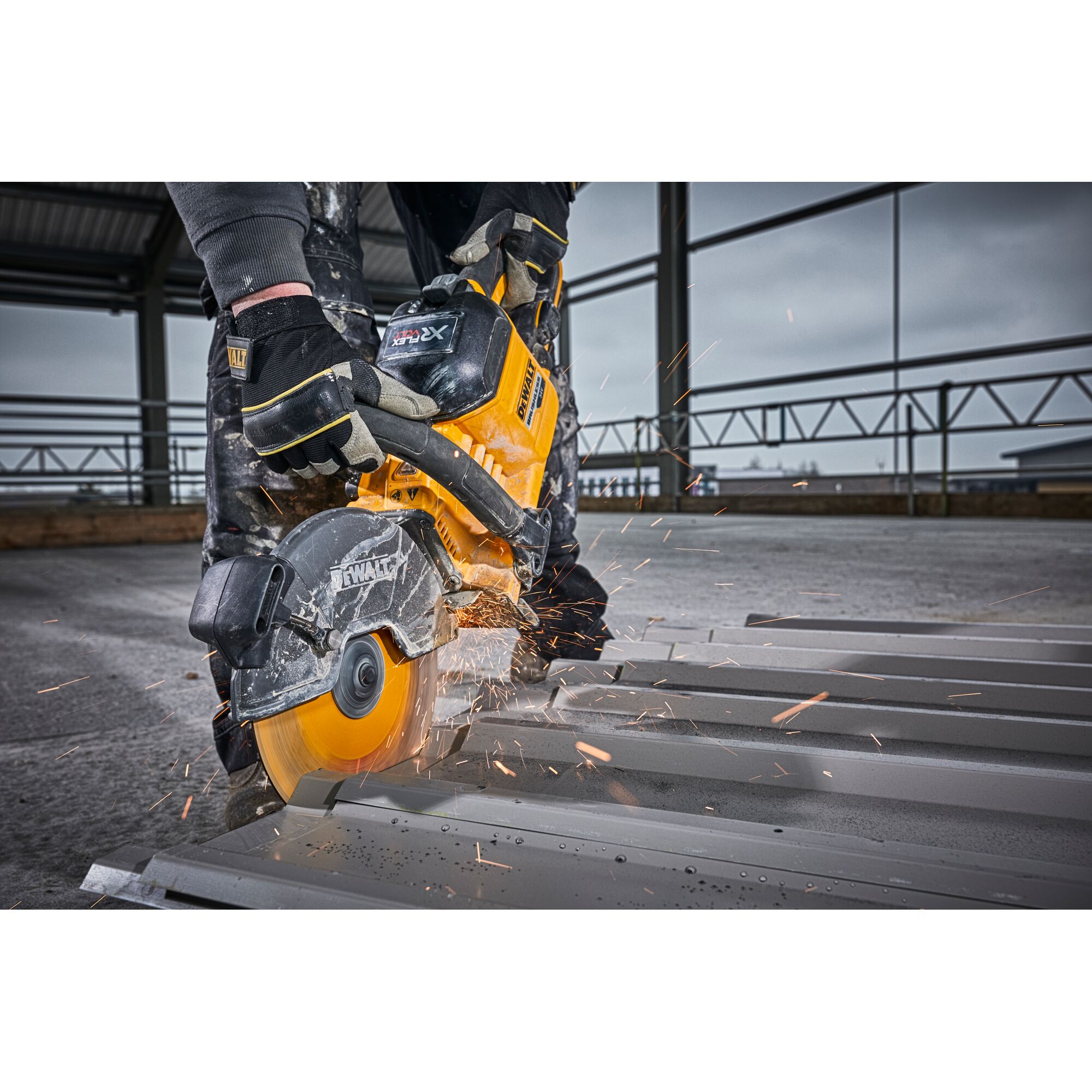 DEWALT saw cutting metal with sparks flying, operated by a person wearing gloves on an industrial site.