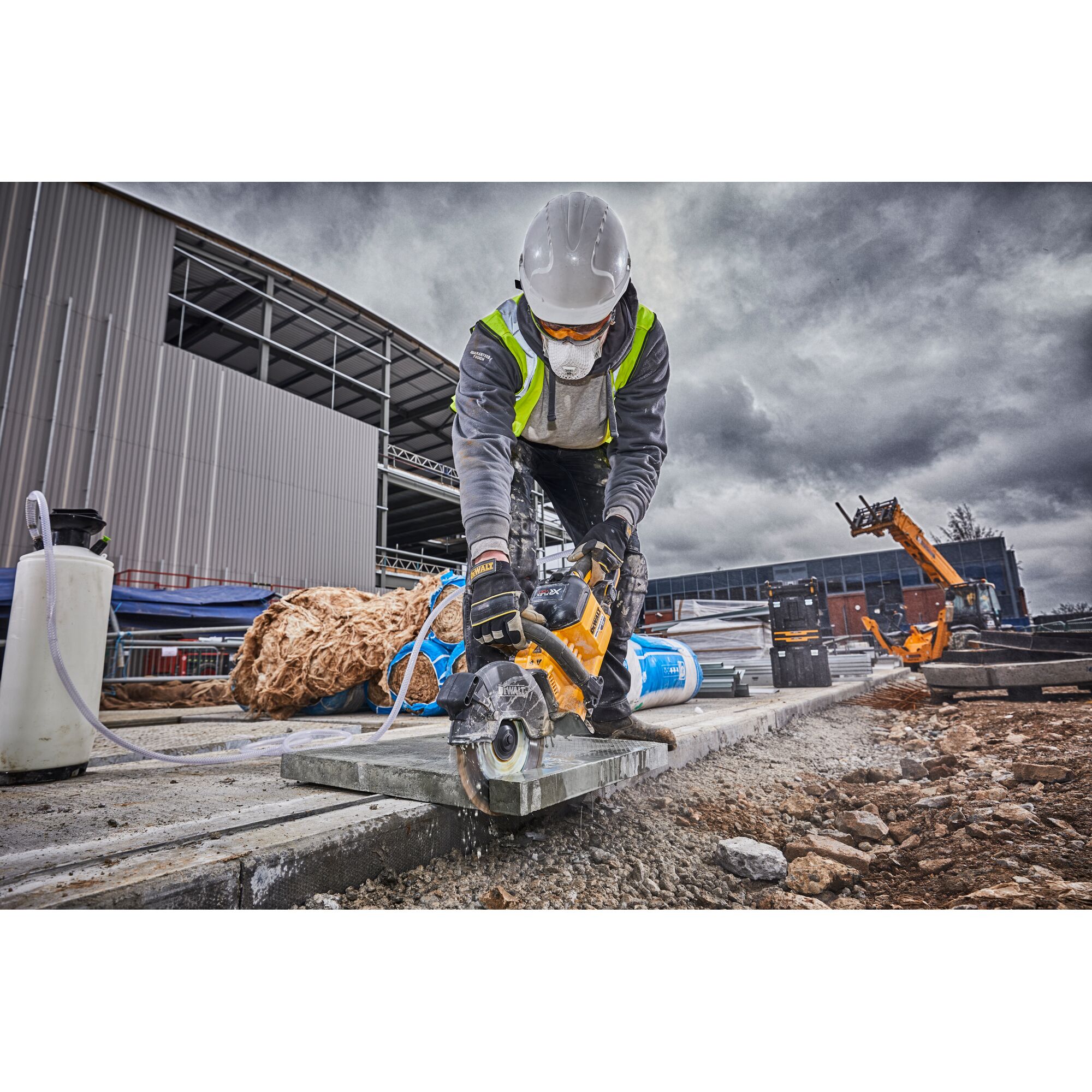 Worker using DEWALT DCS690N cutting tool on stone slab at outdoor construction site.
