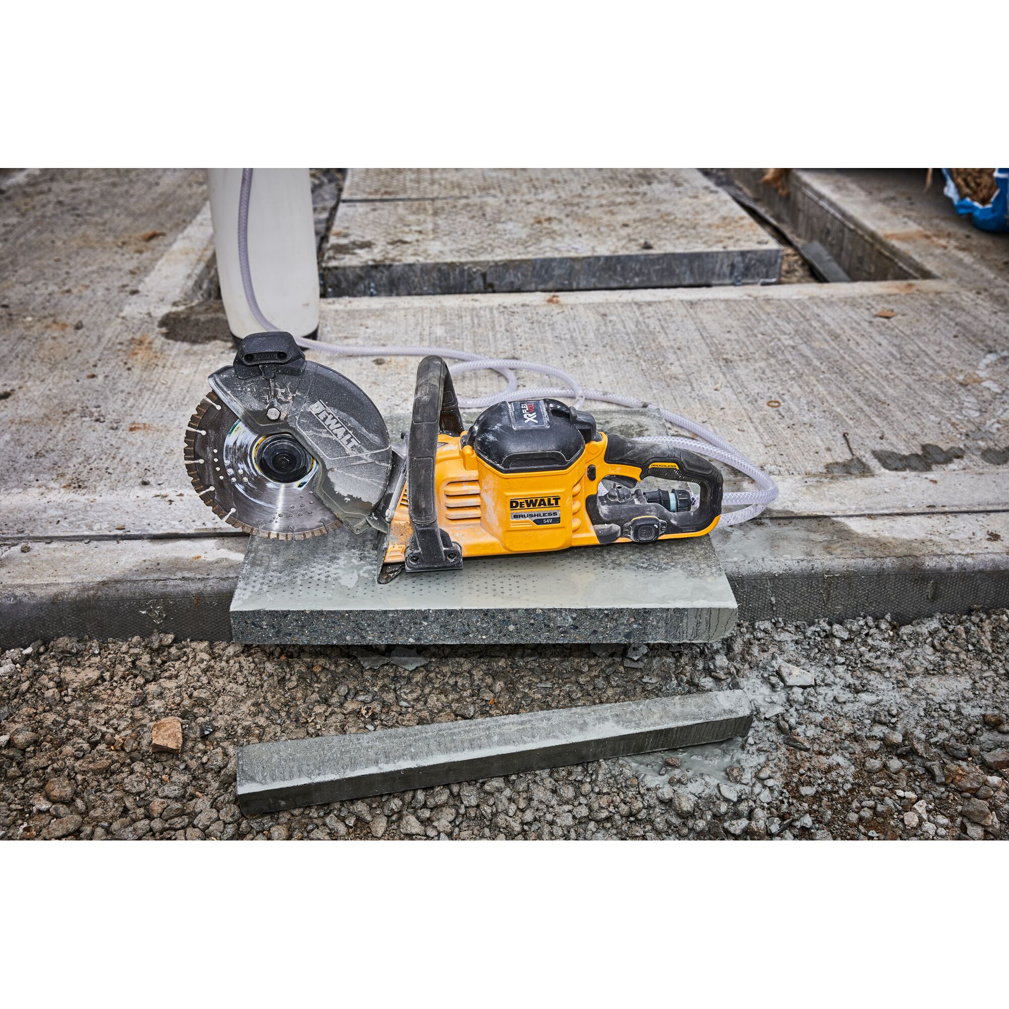 DEWALT DCS690N saw placed on a concrete slab at a construction site, surrounded by gravel and cut stone.