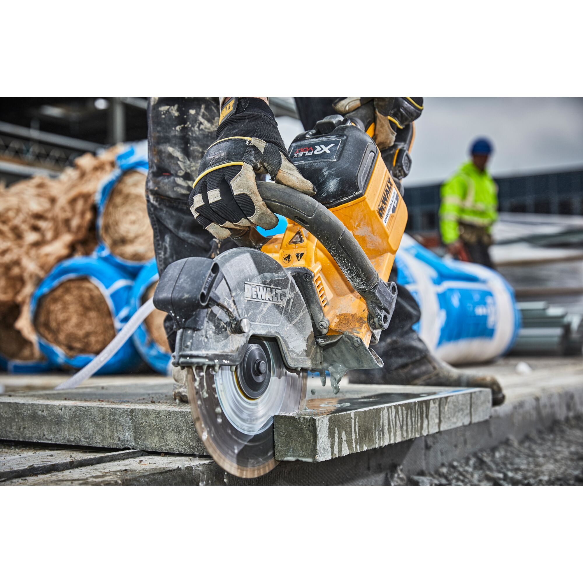 Worker uses a DEWALT DCS690N circular saw to cut concrete at a construction site.