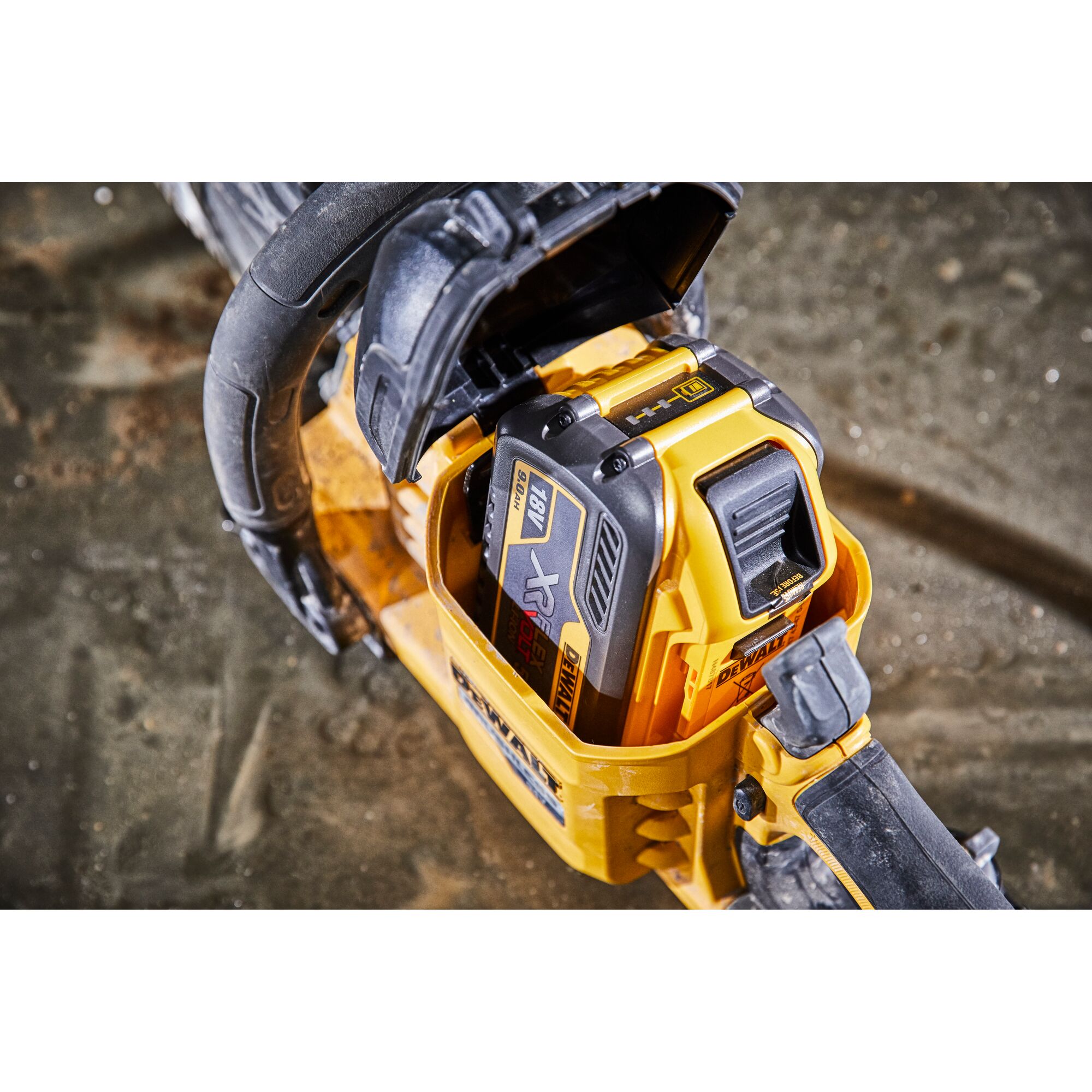 Close-up of a DEWALT cordless power tool with an 18V battery installed, placed on a dusty surface.