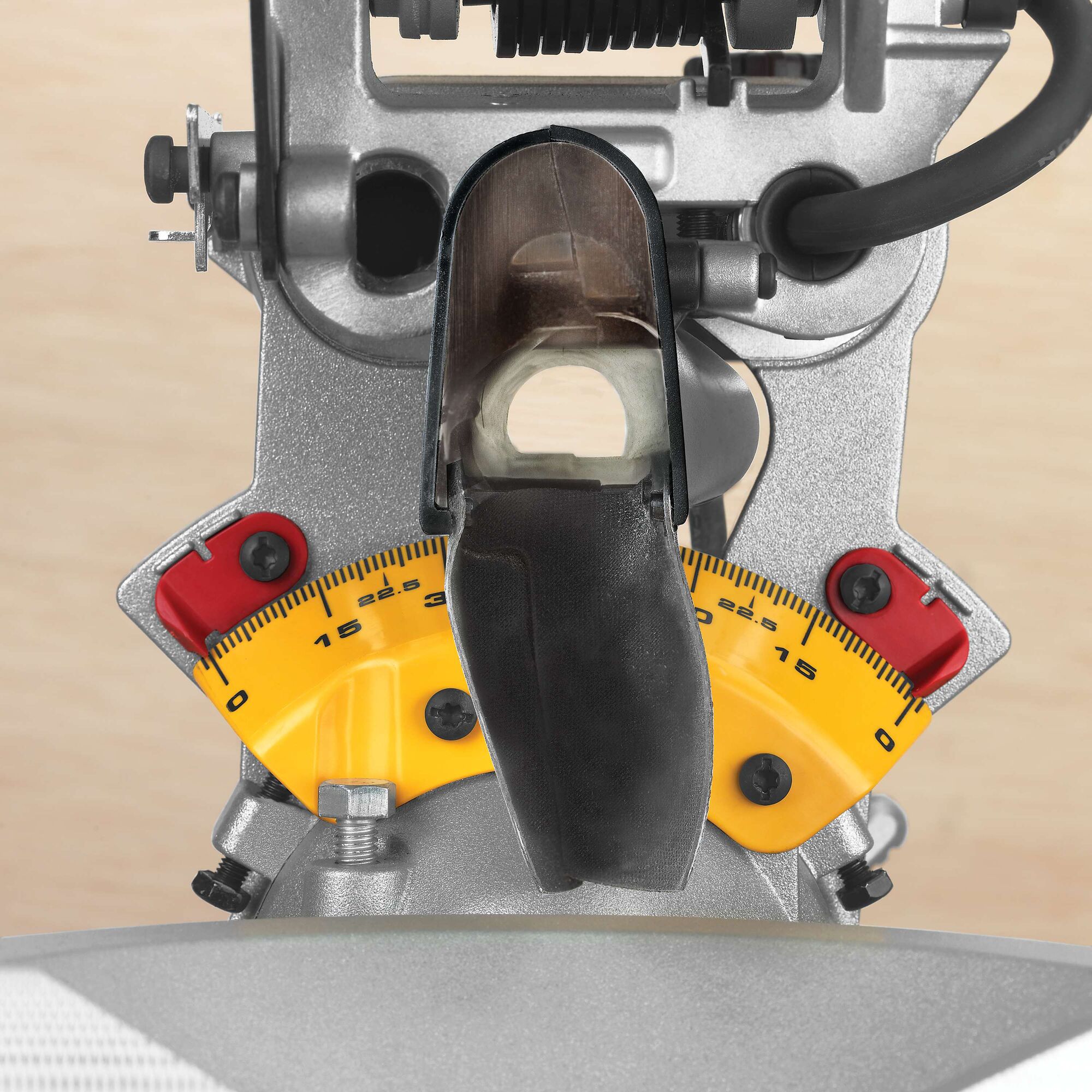 Close-up view of a DEWALT DWS780 miter saw showing the yellow angle measurement scale with red adjustment locks and metal components.
